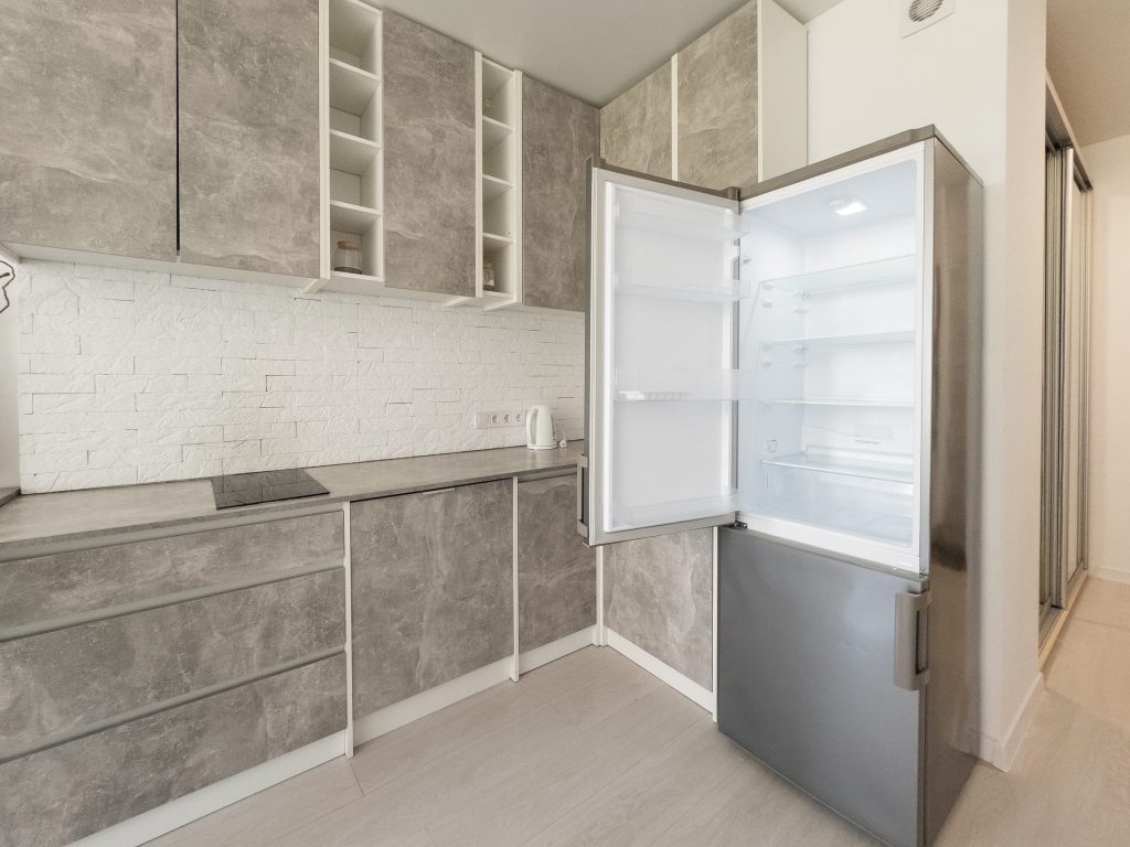 a compact bottom-freezer standing open and empty, the freezer drawer below