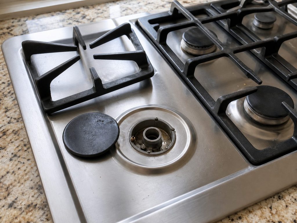 one grate lifted and the burner cap tipped beside it, the igniter visible