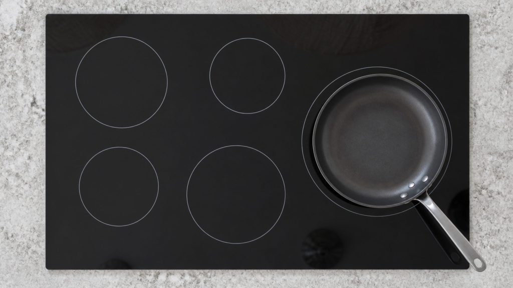 an induction cooktop straight down, the zones printed as plain rings on black glass