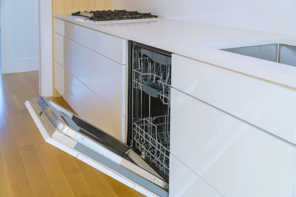 a freestanding dishwasher standing open in a light kitchen run