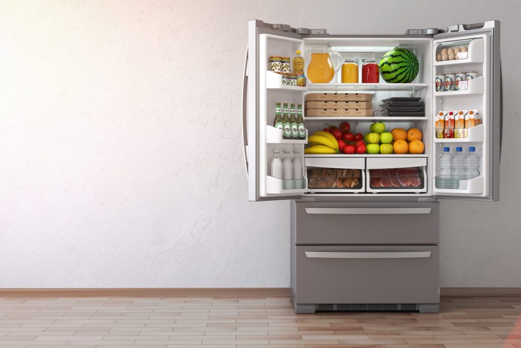 a French-door cabinet standing open on a stocked interior with the freezer drawers below