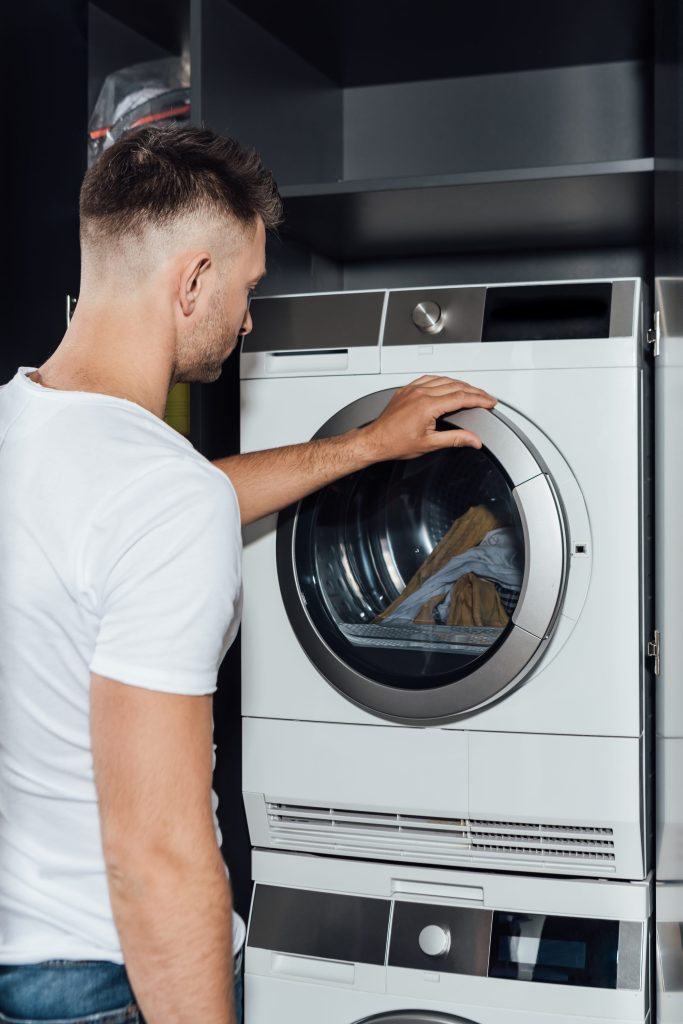 a stacked pair set into a cabinet, the upper machine open on a load