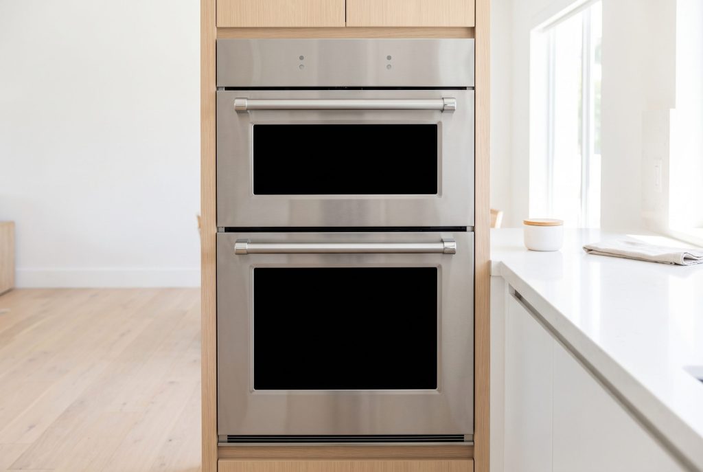 a double wall oven with two black glass panels and a bar handle between them