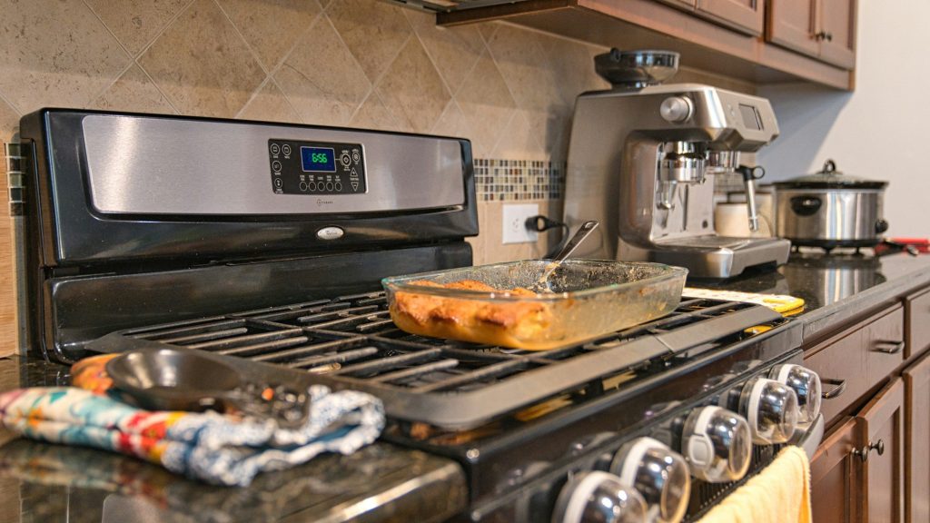a stainless gas range with cast grates in a kitchen of dark cabinets
